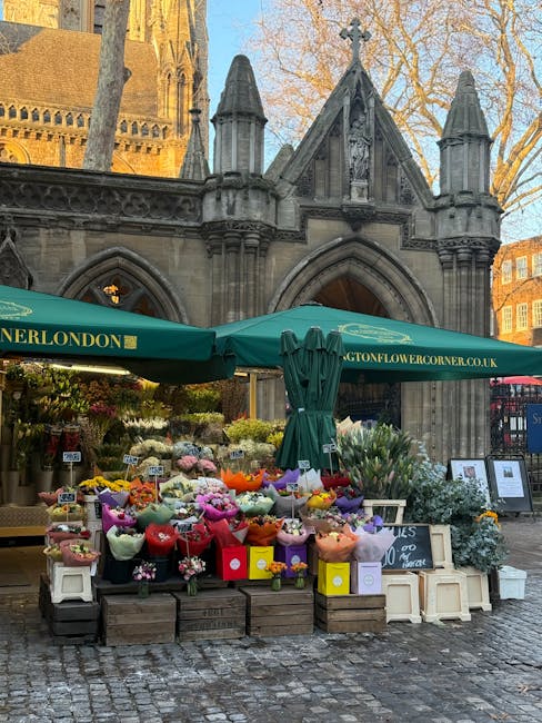An outdoor flower stall situated in front of a historic stone church with intricate gothic architecture and pointed arches, offering a vibrant array of fresh flowers including roses, tulips, daisies, 