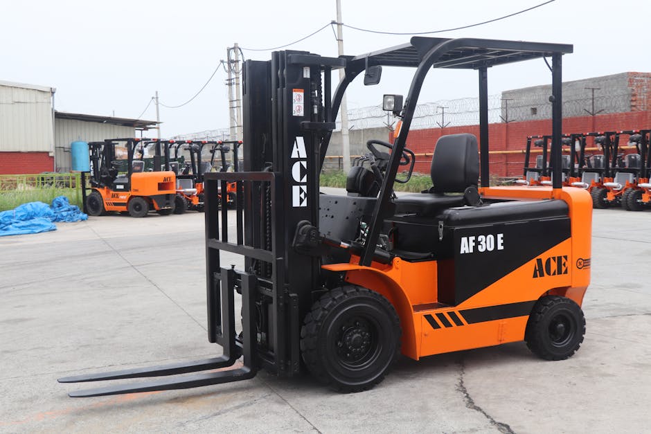 A bright orange and black ACE AF30E forklift with a protective overhead canopy, parked on a concrete surface outdoors. In the background, several similar forklifts are lined up, with some covered by b